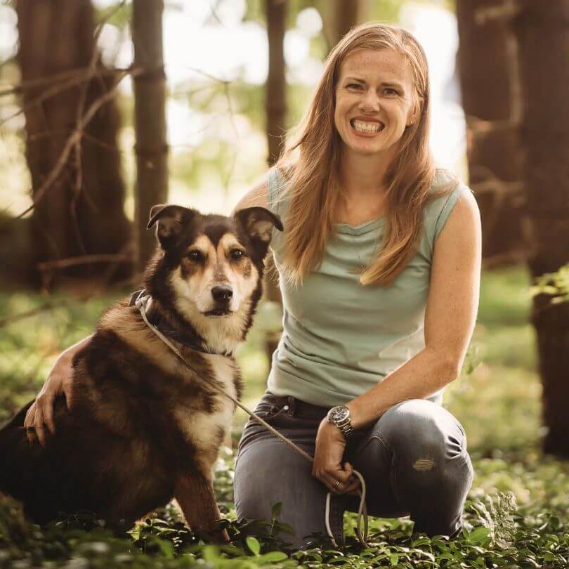 Dr. Morgan in the woods with her dog