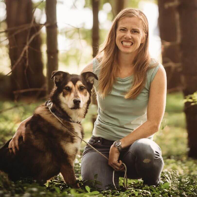 Dr. Morgan in the woods with her dog