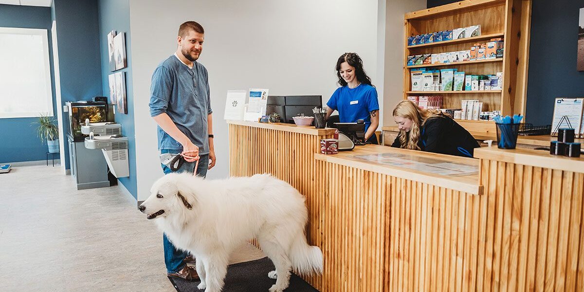client and his dog at the front desk with two smiling receptionists
